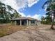 Rear exterior view of a modern home design with a covered patio and a spacious lot with tropical trees at 1495 Craleigh St, North Port, FL 34288