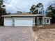 Charming gray home featuring a three-car garage and a brick paver driveway at 1495 Craleigh St, North Port, FL 34288