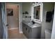 Bathroom featuring a gray vanity with sleek, black hardware and modern, illuminated mirror with shelves at 1884 Coconut Palm Cir, North Port, FL 34288