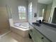 Bright bathroom featuring a large tub under two windows, separate shower, and vanity with dark hardware at 1884 Coconut Palm Cir, North Port, FL 34288