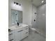 Modern bathroom with shower and toilet area with marble floors, a single sink and white cabinets at 16475 Hillsborough Blvd, Port Charlotte, FL 33954