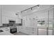 Open kitchen boasts white cabinets, an island, modern appliances, and stylish pendant lights at 1740 Lucas Dr, Clearwater, FL 33759