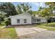 Single-story home with a cozy porch and well-kept lawn, complemented by a paved driveway and mature trees at 1937 N Highland Ave, Clearwater, FL 33755