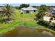 A serene backyard view features a lush green lawn leading to a tranquil pond, fringed by vibrant vegetation and mature palms at 27 Bunker Ct, Rotonda West, FL 33947