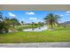 Picturesque backyard view overlooks a peaceful canal with lush landscaping, mature palms, and clear blue skies above at 27 Bunker Ct, Rotonda West, FL 33947