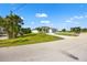 A contemporary home boasts an attached garage and a long, paved driveway surrounded by lush landscaping at 27 Bunker Ct, Rotonda West, FL 33947
