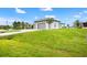 A modern home features an attached garage, a well-kept lawn, and a long, paved driveway at 27 Bunker Ct, Rotonda West, FL 33947