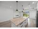 A modern kitchen featuring a large island, granite countertops, stylish pendant lights, and stainless steel appliances at 27 Bunker Ct, Rotonda West, FL 33947