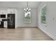Bright dining room features hardwood floors, a modern chandelier, and two large windows with backyard views at 9739 Loretto St, Spring Hill, FL 34608