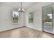 Bright dining room with hardwood floors, a modern chandelier, large windows, and access to a door at 9739 Loretto St, Spring Hill, FL 34608