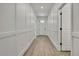 Hallway with light-colored wood floors, and wainscotting on the white walls, leading to a front door at 9739 Loretto St, Spring Hill, FL 34608