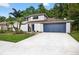 Charming two-story home with blue garage door and landscaped front yard with trees and white brick accents at 4404 Grainary Ave, Tampa, FL 33624