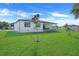 Spacious backyard with green lawn, featuring a young tree in center at 3323 Elkcam Blvd, Port Charlotte, FL 33952