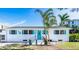 Charming front exterior with a light blue door, white brick, and lush tropical landscaping at 4311 123Rd W St, Cortez, FL 34215