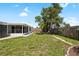 Grassy backyard featuring a privacy fence, patio, and mature tree providing shade at 3410 Allandale Dr, Holiday, FL 34691