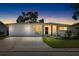 Charming single-story home with a manicured lawn, stucco exterior, and attached garage at dusk at 3410 Allandale Dr, Holiday, FL 34691