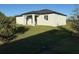 An inviting backyard showing off a modern home and flourishing green lawn with ample natural light at 10071 Kingsville Dr, Port Charlotte, FL 33981