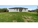 Expansive backyard featuring lush grass, a covered patio, and an open view at 10071 Kingsville Dr, Port Charlotte, FL 33981
