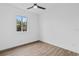 Clean bedroom with wood-look floors, a ceiling fan, a large window, and crisp white paint at 10071 Kingsville Dr, Port Charlotte, FL 33981