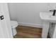 Contemporary powder room with a modern sink and toilet on wood flooring at 10071 Kingsville Dr, Port Charlotte, FL 33981