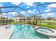 Beautiful screened-in pool and spa surrounded by lush landscaping and a black safety fence at 10720 Breaking Rocks Dr, Tampa, FL 33647