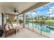 Covered patio with wicker furniture overlooks a sparkling screened-in pool and lush landscaping at 10720 Breaking Rocks Dr, Tampa, FL 33647