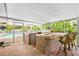 Screened outdoor kitchen with brick counters, built-in grill, sink, and bar seating overlooking pool at 1302 Georgetowne Cir, Sarasota, FL 34232