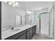 Bathroom featuring dual sinks, gray cabinets, and a glass-enclosed shower at 9581 Vibrant Lane, Venice, FL 34292