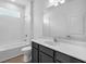 Clean bathroom with white tiles, dark vanity, white countertop, and a tub with a shower head at 9581 Vibrant Lane, Venice, FL 34292