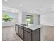 Kitchen island with stainless steel sink and appliances, as well as gray lower cabinets and an open floor plan at 9581 Vibrant Lane, Venice, FL 34292