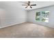 Bright, carpeted bedroom with neutral walls, a ceiling fan, and a large window for natural light at 10344 Rosemount Dr, Tampa, FL 33624