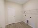 Bright laundry room with wood-look flooring, a white door, wire rack shelving, and utility connections at 11818 Tetrafin Dr, Riverview, FL 33579