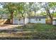 View of the home's backyard with mature trees, a privacy fence, and a glimpse of the white exterior walls at 709 1St Ne Ave, Largo, FL 33770