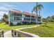 Inviting condo building with lush landscaping, mature palm trees, and private balconies on both levels at 3805 E Bay Dr # 204, Holmes Beach, FL 34217