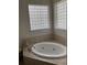 Inviting soaking tub surrounded by tile and illuminated by glass block windows at 10533 Hazel St, Largo, FL 33778