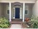 Inviting entryway with a blue front door, white columns, and beautiful landscaping at 10533 Hazel St, Largo, FL 33778