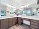 Bright bathroom features a vanity with double mirrors, a glass shower, and sleek wood tile flooring at 15503 Corona Del Mar Dr, Wimauma, FL 33598
