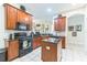 Kitchen featuring wood cabinets, black appliances, an island, and tile floors at 20074 Heritage Point Dr, Tampa, FL 33647