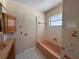 Bathroom with tiled walls, a pink bathtub, and a window at 5627 Oakland Dr, Tampa, FL 33617