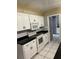 Efficient kitchen featuring white cabinets, black countertops, and tiled flooring at 4650 Orlando Cir, Bradenton, FL 34207