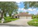 Beautiful exterior view of home featuring lush landscaping, mature trees, and a three-car garage at 15007 Laurel Cove Cir, Odessa, FL 33556