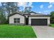 Inviting single-story home with lush lawn, gray roof, dark garage door, and stylish architectural details at 3913 Eagle Pass St, North Port, FL 34286