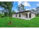 Modern home exterior featuring a white stucco facade, a covered patio, and a lush green lawn at 3913 Eagle Pass St, North Port, FL 34286