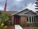 Close-up of brick home with a bright red door, and manicured landscaping at 1403 Ventana Dr, Sun City Center, FL 33573