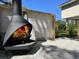 Outdoor cone fireplace with flames, pea gravel, and fenced yard at 1300 Pleasant S Way, St Petersburg, FL 33705