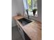 Close up of a modern kitchen sink with wood countertop and potted plants in the window at 1300 Pleasant S Way, St Petersburg, FL 33705