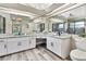 Well-lit bathroom with dual sinks, granite countertops, modern fixtures, and a tiled shower, complemented by wood-look floors at 13295 Don Loop, Spring Hill, FL 34609