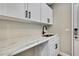 Bright laundry room with white cabinets, black hardware, and marble countertop at 13295 Don Loop, Spring Hill, FL 34609