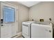 Bright laundry room features a white front-loading washer and dryer next to a white door with window at 13295 Don Loop, Spring Hill, FL 34609