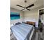 Cozy bedroom with stylish ceiling fan, blue art, wood-look floors, and adjacent desk area at 15301 Chinook Way, Port Charlotte, FL 33981